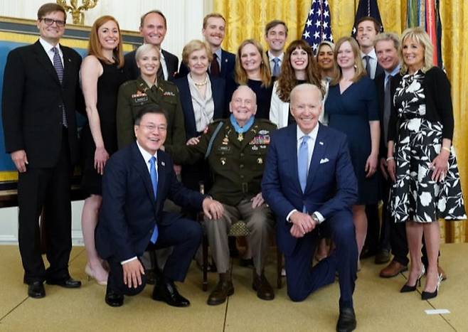 지난 5월 21일 미국 워싱턴 백악관에서 명예훈장을 받은&nbsp;랠프 퍼킷 예비역 육군 대령(가운데 의자에 앉은 인물)이 양옆에 나란히 무릎을 꿇은 문재인 대통령, 조 바이든 미국 대통령, 그리고 가족 등과 기념촬영을 하고 있다. 세계일보 자료사진