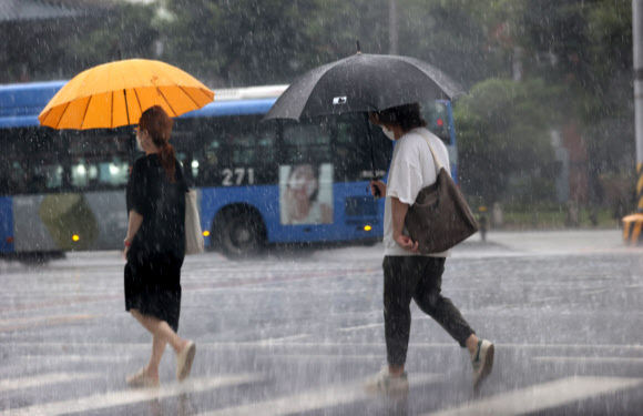 1일 서울 종로구 도로에서 시민들이 우산을 쓴 채 발걸음을 옮기고 있다. 기상청은 이날 전국이 대체로 흐리고 대부분 지역에서 비가 내리며 습도가 높아져 체감온도가 상승해 폭염이 이어질 것으로 예보했다. 연합뉴스