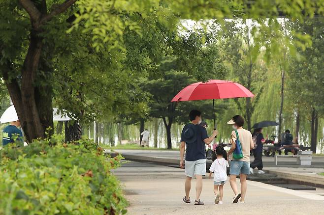1일 서울 영등포구 한강공원에서 시민들이 우산을 쓴 채 발걸음을 옮기고 있다. 기상청은 이날 전국이 대체로 흐리고 대부분 지역에서 비가 내리며 습도가 높아져 체감온도가 상승해 폭염이 이어질 것으로 예보했다. 연합뉴스