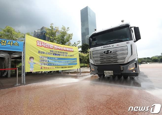 3일 오후 서울 여의도공원에 마련된 임시선별진료소에서 살수차가 열기를 식히기 위해 도로에 물을 뿌리고 있다. 2021.8.3/뉴스1 © News1 신웅수 기자