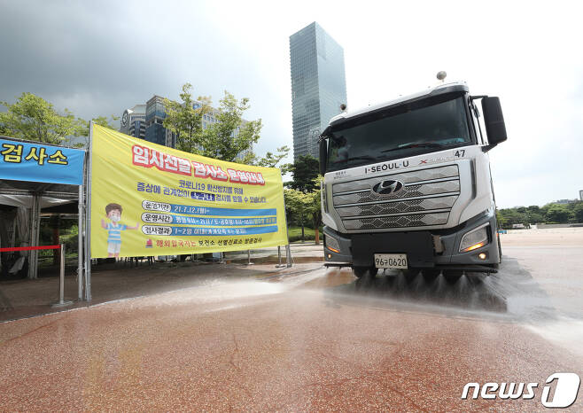 3일 서울 여의도공원에 마련된 임시선별진료소에서 살수차가 열기를 식히기 위해 도로에 물을 뿌리고 있다. 2021.8.3/뉴스1 © News1 신웅수 기자