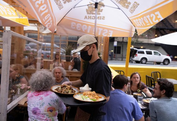 지난 3일(현지시간) 미국 뉴욕 맨해튼의 한 식당에서 점원이 마스크를 쓴 채 음식을 나르고 있다.로이터뉴스1