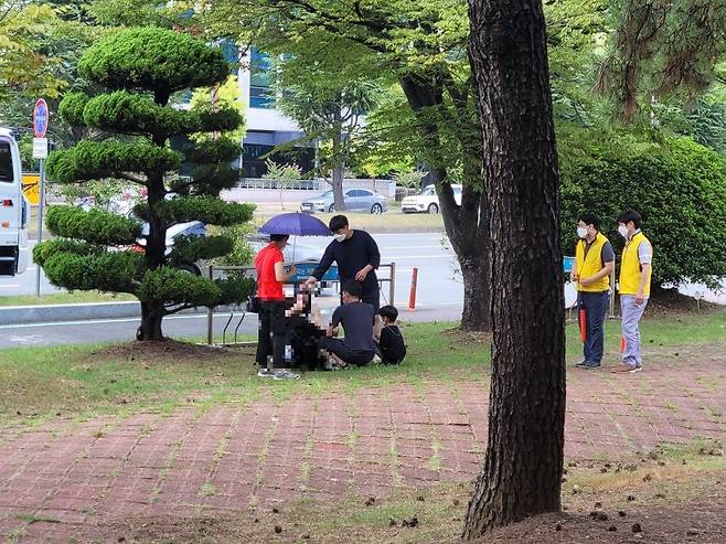 5일 오후 1시 20분쯤 경남 창원시 성산구 용지문화공원에 마련된 선별검사소에서 검사를 받기 위해 줄을 섰던 한 여성이 더위에 지쳐 쓰러졌다. 주변 시민들이 여성을 부축하고 있다. /독자제공