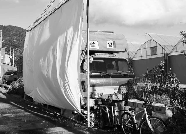 마당 앞에 설치된 스크린 뒤로 신지승 감독 가족이 타고 다닌 5t 트럭이 보인다. 영화 촬영 장비를 싣고 차안에서 숙박하며 온가족이 살았던 시절을 잊지 못해 폐차하지 못하고 유물처럼 두고 있다.