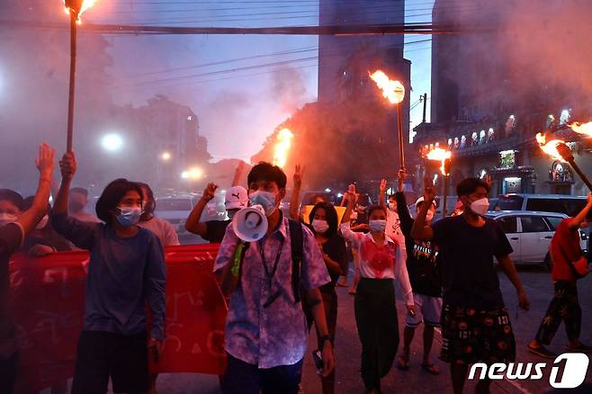 지난달 29일(현지시간) 미얀마 양곤서 열린 군사 쿠데타 반대 시위에서 시위대가 횃불을 든 채 세 손가락 경례를 하고 있다. © AFP=뉴스1 © News1 서한샘 기자