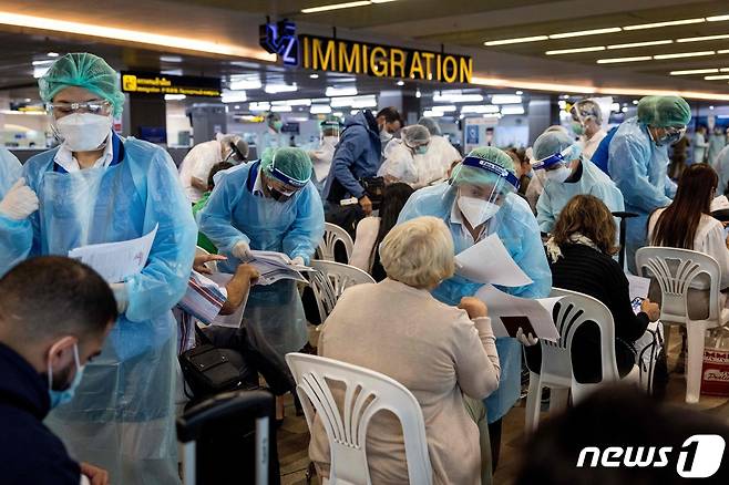 11일 (현지시간) 태국 푸켓 공항에서 방호복을 입은 공항 직원들이 카타르 도하서 도착한 승객들의 여권을 확인하고 있다. © AFP=뉴스1 © News1 우동명 기자