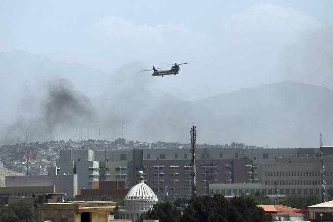 아프가니스탄 무장단체인 탈레반이 수도 카불을 포위한 15일(현지시간) 미군의 치누크 수송헬기가 카불에 남아 있는 미국인들의 탈출을 돕기 위해 대사관 건물을 향해 날아가고 있다. 카불|AP연합뉴스