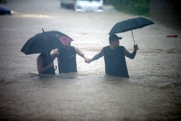 게릴라성 호우 무서운데 - 호우 경보가 내려지면서 게릴라성 집중호우가 쏟아진 18일 새벽 강원 강릉 시내에서 젊은이들이 서로 손을 잡고 침수된 도로를 건너고 있다. 2021.8.18 연합뉴스