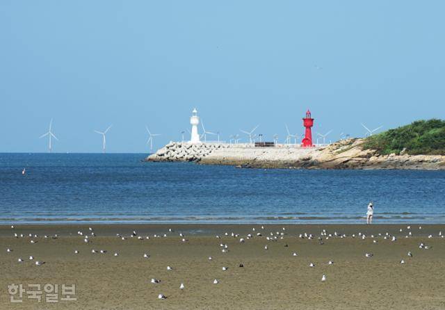 구시포항 등대와 해상풍력발전기가 배경으로 펼쳐지는 구시포해수욕장.