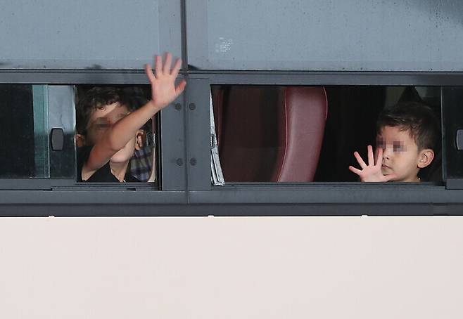 Children of the Afghan nationals who recently arrived in South Korea wave their hands from a bus. (Lee Jong-keun/The Hankoyreh)