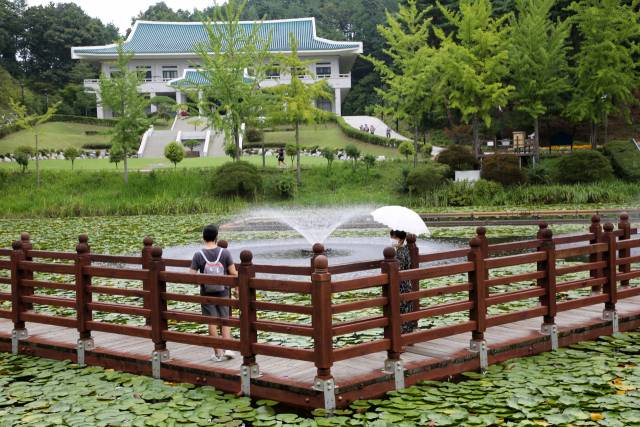 청남대 관람객들이 연못 위 데크에서 분수를 보며 더위를 식히고 있다. 연못은 양어장으로 쓰이다 겨울 스키장으로 사용되기도 했다. 분수대는 김대중 정부 때 설치됐다.