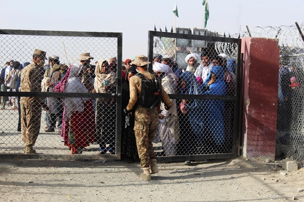 지난달 27일 파키스탄 차만 국경 검문소에서 한 군인이 관문을 걸어잠그고 있다. 밖으로는 파키스탄 진입을 기다리는 아프가니스탄 피난민들이 보인다./AFP 연합뉴스