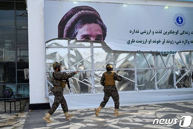 (카불 AFP=뉴스1) 우동명 기자 = 31일(현지시간) 미군이 철수를 완료한 아프가니스탄의 카불 공항에서 아프간 국부로 불리는 아흐마드 샤 마수드의 사진을 탈레반 군들이 찢고 있다.  (C) AFP=뉴스1