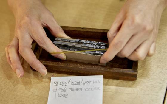 완성된 조판은 고무줄로 바깥 부분을 꽉 고정한다. 손에 힘을 줘 활자가 빠지지 않도록 유의한 뒤 빠르게 인쇄기 위로 옮긴다.