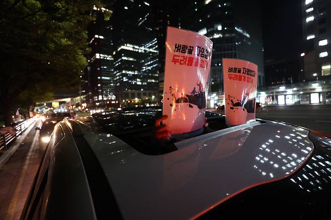 Signs reading “small business owners are at the edge, (we) have nothing to fear” are being held up through a car sunroof during a late night protest in Seoul. (Yonhap)