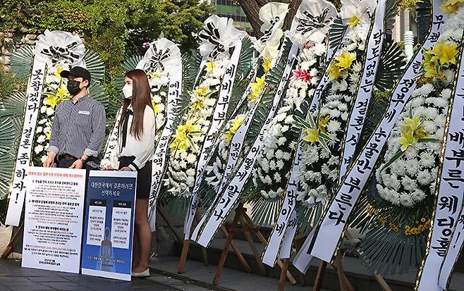 9일 오전 전국신혼부부연합회 회원들이 서울 종로구 세종로공원에서 정부의 결혼식 방역 지침 개선을 요구하는 ‘화환 시위’를 벌이고 있다. ‘답도 없는 결혼식 방역’ ‘못 참겠다! 결혼 좀 하자!’ 같은 글귀가 화환에 걸려 있다. 이들은 정부서울청사 앞에서 시위를 열려고 했으나, 경찰 통제에 막혀 이곳으로 장소를 옮겼다. /연합뉴스