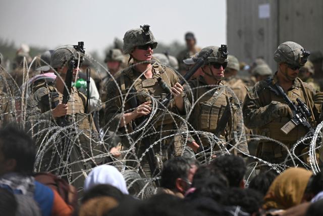 지난달 20일 아프가니스탄 수도 카불의 하미드 카르자이 국제공항에 배치된 미군 병사들이 국외 탈출을 위해 공항 담장 밖에 몰려든 아프간 민간인들을 바라보고 있다. 카불=AFP 연합뉴스