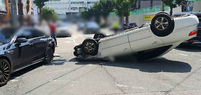 [부산=뉴시스] 11일 부산 동구 시민회관 앞 도로에서 그랜저 승용차가 주차된 벤츠 차량을 들이받고 전복됐다. (사진=부산경찰청 제공) *재판매 및 DB 금지