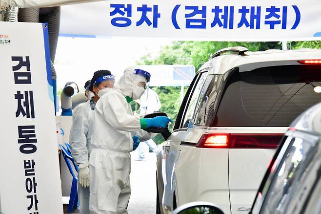 지난 10일 오전 서울 망우저류조공원 드라이브스루 임시선별검사소 일일 진행요원으로 나선 류경기 중랑구청장이 코로나19 검사를 위해 대기하는 시민에게 검체통을 전달하고 있다. 중랑구 제공/연합뉴스