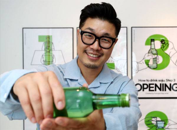 `알랑말랑 소주 탐구생활`을 출간한 퍼니준 작가가 서울 성북동 자택에서 포즈를 취하고 있다. 벽에 보이는 그림은 `소주 마시는 법`을 10단계로 그린 일러스트다. [김호영 기자]