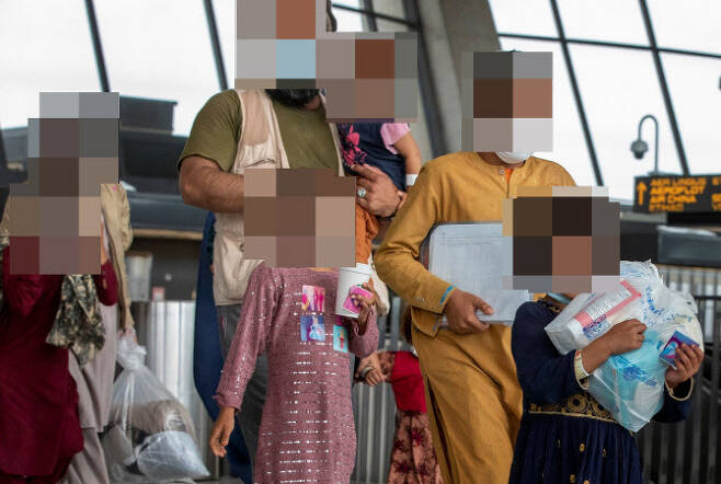 이슬람 무장세력 탈레반이 장악한 아프가니스탄을 탈출한 피란민 가족들이 지난달 31일(현지시간) 미국 버지니아주 챈틸리 공항에 도착한 뒤 버스를 타기 위해 걸어가고 있다. (사진=연합뉴스)