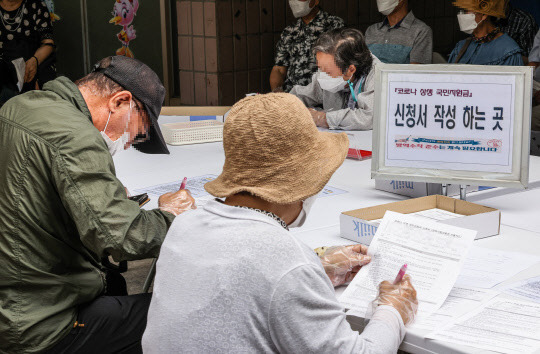 코로나19 상생 국민지원금 대면 신청 첫날인 13일 오전 서울 동작구 대방동 주민센터를 찾은 어르신들이 신청서 작성을 하고 있다. 연합뉴스