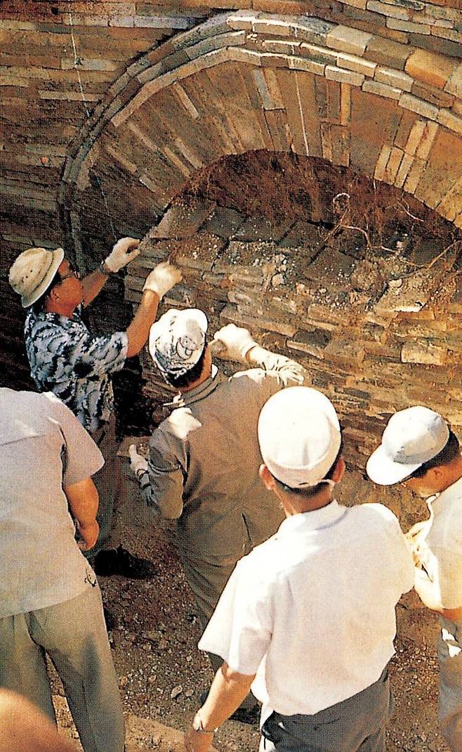 1971년 7월 조사단원들이 무령왕릉의 아치형 입구 연도(널길)를 가로막았던 벽돌들을 빼고 있는 모습이다. 입구 연도 구멍을 빽빽히 채웠던 벽돌들을 걷어내고 묘실 내부로 들어간 조사단은 이후 몰려든 취재진과 주민들에 겁을 먹고 하룻밤 새 유물들을 모두 쓸어담는 패착을 두게 된다. 국립문화재연구소 제공
