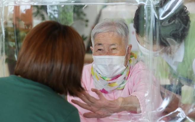 “왔니…” 칸막이 넘어 가슴에 닿는 그리움 경북 상주시 한 요양원에서 13일 며느리와 시어머니가 비닐판을 사이에 둔 채 만나고 있다. 정부는 추석 특별방역대책으로 이날부터 오는 26일까지 요양병원과 요양시설에서 환자와 면회객 모두 백신 접종을 마친 경우 접촉 면회, 그렇지 않으면 비접촉 면회를 할 수 있도록 했다.  연합뉴스