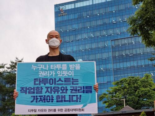 김도윤 타투유니온지회장이 지난 5월 28일 서울북부지법 앞에서 타투이스트 작업할 자유와 권리를 주장하는 피켓을 들고 있다. 연합뉴스