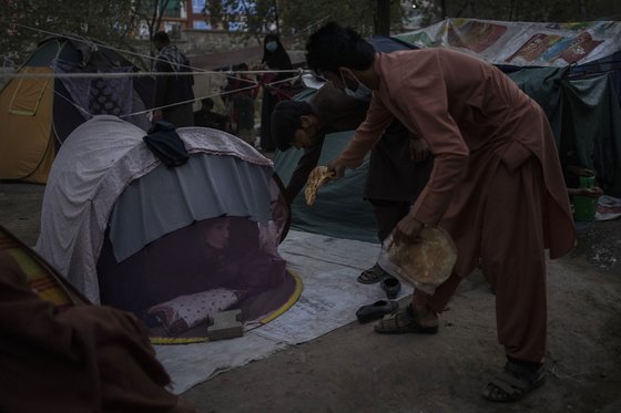 한 남성이 아프간 수도 카불 공원에 마련된 노숙자 캠프 거주자에게 빵을 나눠 주고 있다. [AP=연합뉴스]
