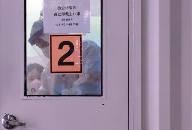 코로나19 선별검사소에서 한 의료진이 검사를 마친 뒤 보건소 관계자와 검사 부스 소독을 하고 있다. /연합뉴스