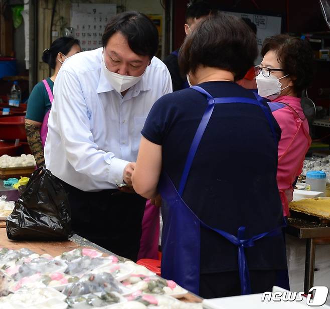 국민의힘 윤석열 대선 경선 후보가 추석 연휴인 18일 경남 창원시 마산합포구 어시장을 찾아 떡을 사고 있다.2021.9.18./뉴스1 © News1 강대한 기자