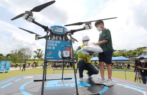 세종시 세종호수공원에서 피자 드론 배송 상용화 서비스를 선보인 8월 22일 오후 한 어린이가 드론으로 주문한 피자를 받아들고 있다. 연합뉴스
