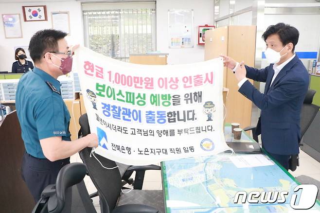 더불어민주당 조승래 의원(대전 유성갑, 오른쪽)이 추석 연휴를 맞아 유성경찰서 노은지구대를 방문, 보이스피싱 예방에 관한 현수막을 들어보이고 있다. (조승래 의원실 제공) ©뉴스1