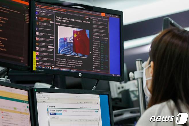(서울=뉴스1) 안은나 기자 = 23일 오전 서울 중구 하나은행 딜링룸에서 딜러가 중국 부동산 개발회사 헝다그룹 리스크 관련 뉴스를 띄워놓고 있다. 추석 연휴가 끝난 이날 원·달러 환율이 1183원에 개장하며 장중 연 고점을 돌파했다. 달러화 강세와 헝다그룹 리스크가 요인인 것으로 풀이된다. 2021.9.23/뉴스1