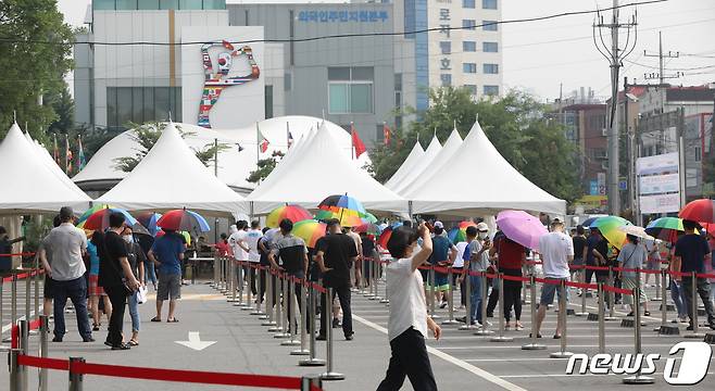 안산시가 지역 산업단지 입주 기업 근로자들에 대한 신종 코로나바이러스 감염증(코로나19) PCR 진단검사 행정명령을 시행한 29일 오전 경기도 안산시 단원구 외국인주민지원본부 옆 주차장에 위치한 임시선별검사소에서 시민들이 코로나19 검사를 받기 위해 줄 서있다. 2021.7.29/뉴스1 © News1 김영운 기자