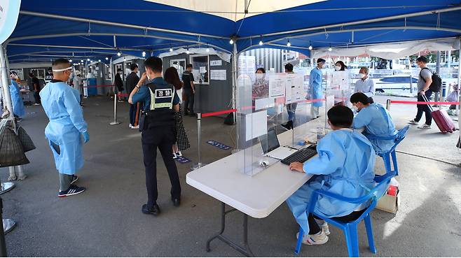 This photo taken Sunday morning shows people waiting at a testing clinic set up outside Seoul Station in the city`s central district. (Yonhap)