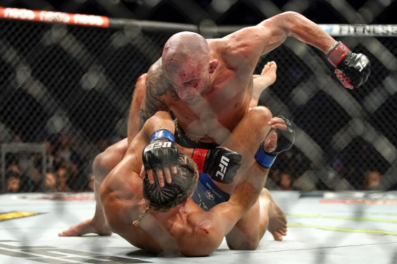 알렉산더 볼카노프스키(위)가 25일(현지시간) 미국 네바다주 라스베이거스에서 열린 UFC 266 메인 이벤트 페더급 경기에서 브라이언 오르테가에게 주먹을 날리고 있다.AP 연합뉴스