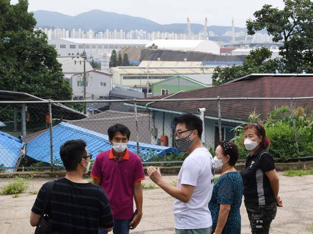 지난달 2일 인천 서구 사월마을 마을회관 뒤편에서 주민들이 기자(맨 왼쪽)에게 사월마을의 오염 피해 상황에 대해 설명하고 있다. 뒤쪽으로 마을에 가득 들어찬 폐기물처리 공장들이 보인다. 인천=홍인기 기자