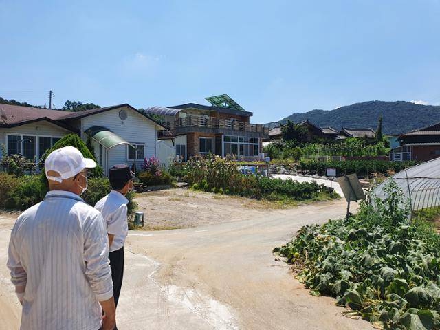 인근 공장에서 오염물질을 배출, 집단 암 발병이 발생했다고 보는 충남 천안 수신면의 주민들이 마을 어귀에서 공장 위치를 설명하고 있다. 전혼잎 기자