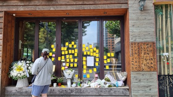 지난 27일 마포 맥줏집 여사장이 운영했던 선술집 유리벽에 시민들이 남긴 추모 메모가 다닥다닥 붙어 있다. 그 아래 놓인 화환에는 ‘자영업자님의 명복을 빕니다’ 라고 씌어 있다. 조강수 기자