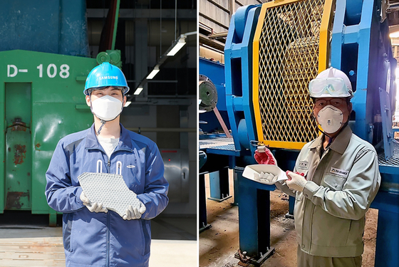 A Samsung Electronics employee, left, and a Pos Ceramics employee pose for a photo holding wastewater sludge and the fluorite alternative product that was made with it. [SAMSUNG ELECTRONICS]