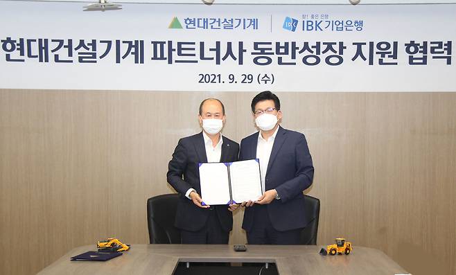 현대건설기계는 29일 경기 분당사무소에서 IBK기업은행과 '협력사 스마트 공장 지원을 위한 업무협약'을 맺었다. 왼쪽부터 박주용 IBK기업은행 부행장, 양경신 현대건설기계 구매본부장.(현대건설기계 제공) © 뉴스1