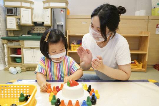 30일 고용노동부는 생후 12개월 자녀를 둔 근로자의 육아휴직 급여를 첫 3달간 통상임금의 100%를 제공하는 내용의 고용보호법 개정안을 입법예고했다. 사진은 입이 보이는 '소통마스크'를 쓴 어린이집 교사와 원아. 연합뉴스.