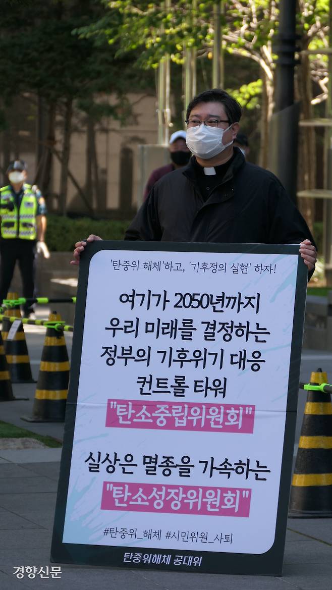 탄중위 해체 공대위에 참여한 남양주 비상행동 활동가 원동일씨가 30일 서울 광화문 탄소중립위 입주 건물 앞에서 열린 종교위원 기자회견 중 ‘탄소중립위원회가 실상은 멸종을 가속하는 탄소성장위원회’라고 적은 팻말을 들고 있다. 김종목 기자