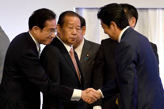 기시다 후미오 자민당 신임 총재와 아베 신조 전 총리가 악수하고 있다./사진=AFP