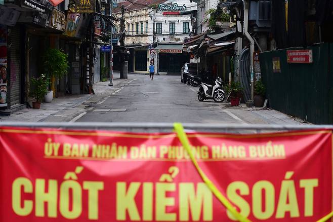 베트남 수도 하노이에서 한 주민이 신종코로나바이러스감염증(코로나19) 봉쇄 조치로 바리케이드가 설치된 식당가를 걸어가고 있다. /AFP 연합뉴스