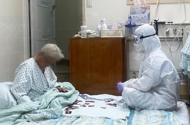 방호복을 입은 간호사가 90대 할머니와 화투를 활용한 그림 맞추기 놀이를 하고 있다. 대한간호협회 제공