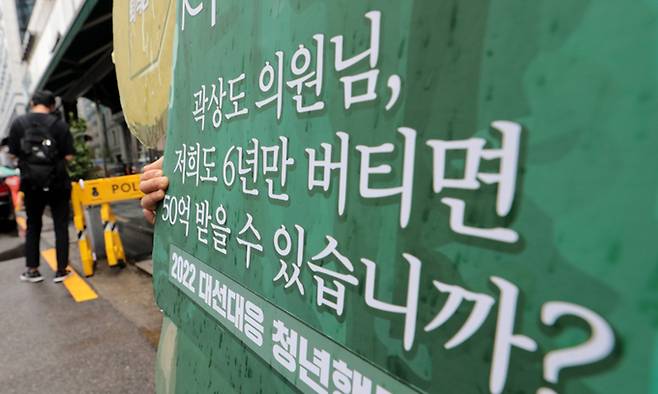 지난달 29일 서울 영등포구 국민의힘 중앙당사 앞에서 2022 대선대응 청년행동 관계자가 곽상도 의원 아들의 50억 퇴직금을 비판하는 피켓을 들고 있다. 뉴스1