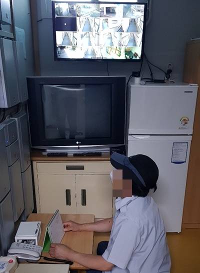 서울 한 중학교 당직 노동자가 30일 좁은 당직실에 앉아 시설물을 모니터링하고 있다.  냉장고, TV 등 생활필수품과 함께 폐쇄회로(CC)TV 같은 보안설비가 들어차 있다. 민주노총 공공운수노조 전국교육공무직본부 서울지부 제공